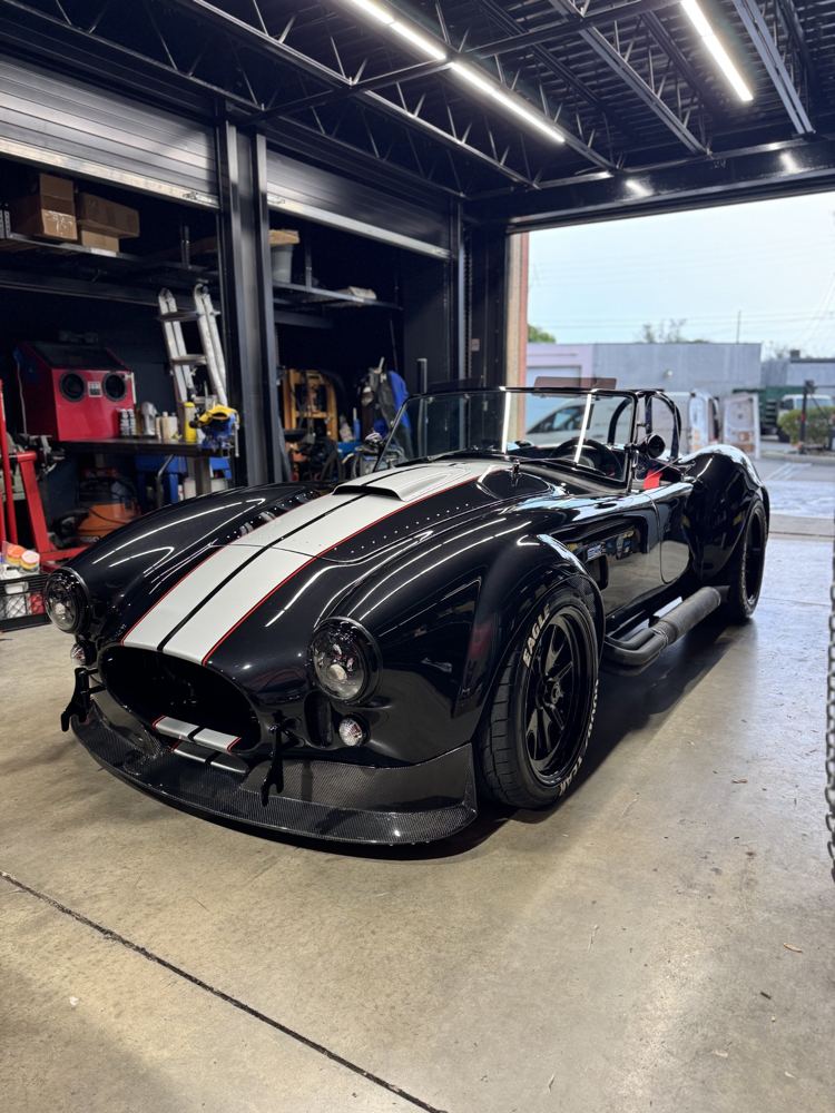 Black Cobra roadster with silver stripes, polished