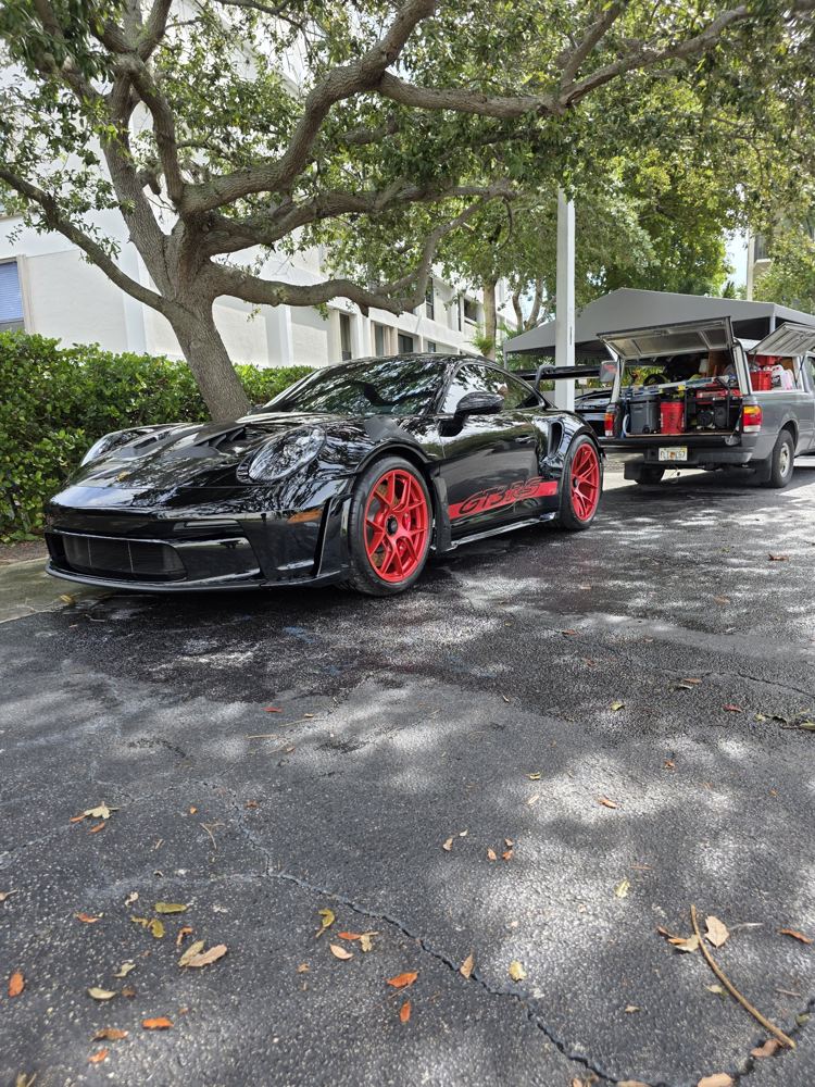 Black Porsche GT3 RS with red wheels after a mobile wash