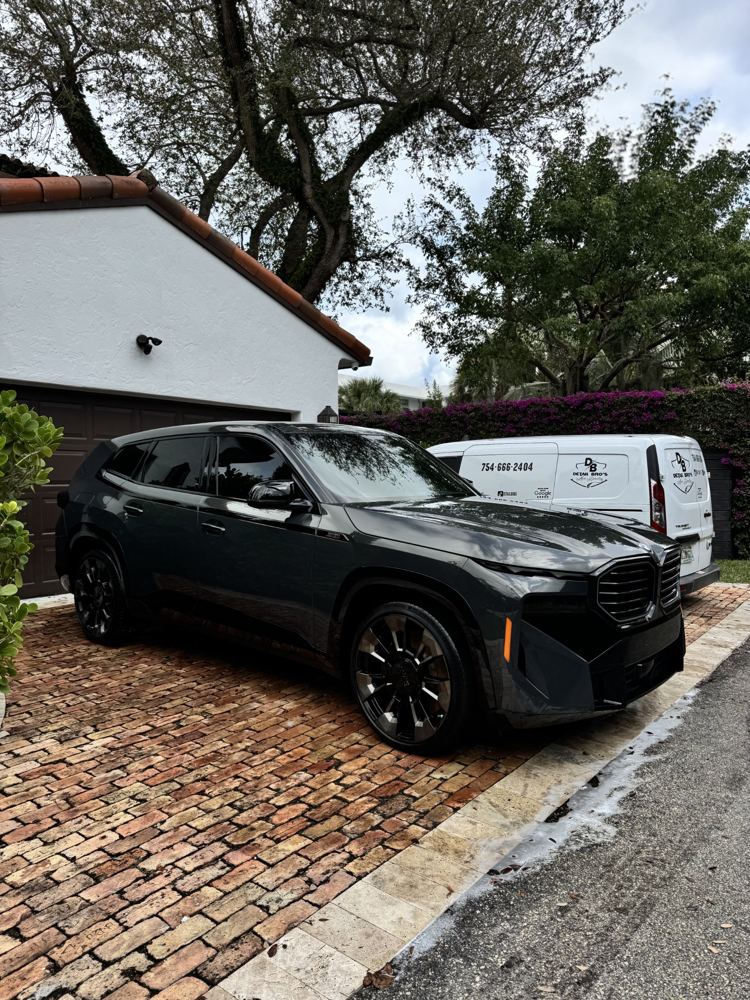 BMW XM in a driveway with the Detail Bros van